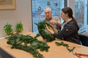 Une homme et une dame confectionnent une couronne